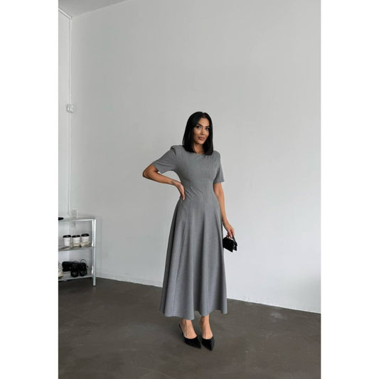 Woman wearing a gray dress standing in a minimalistic room.
